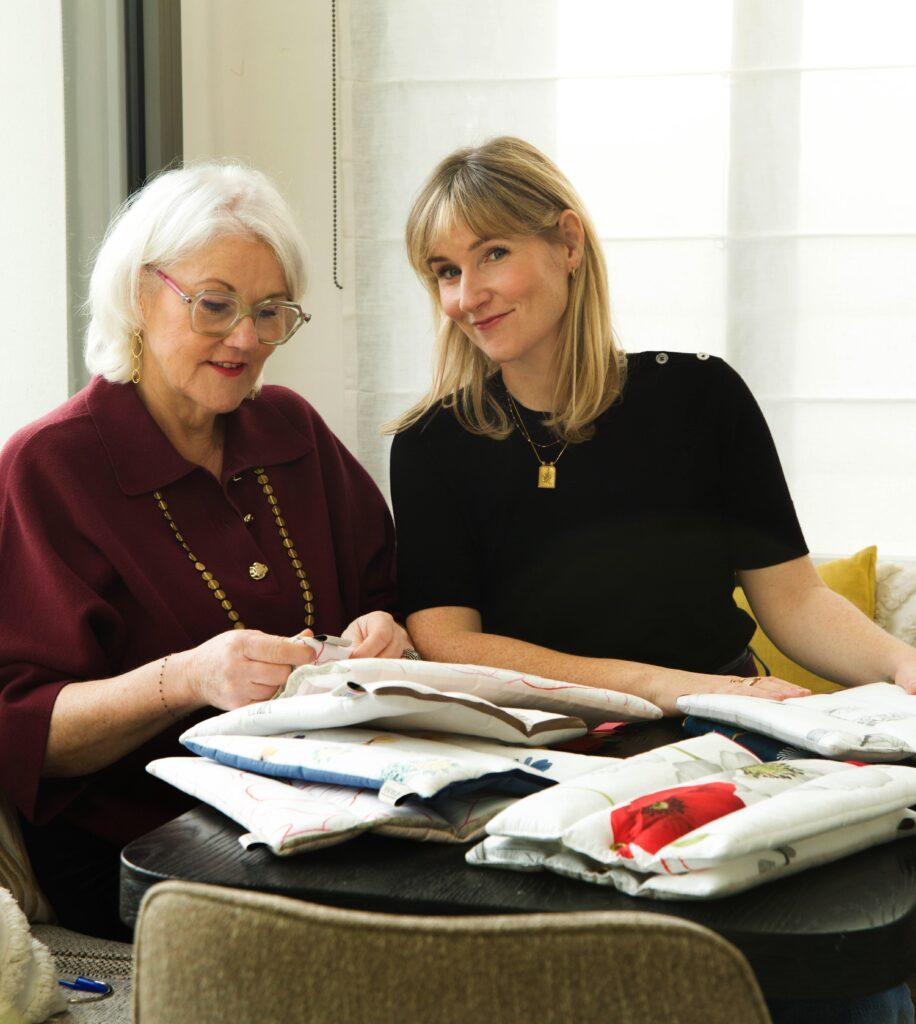 Maryse et Jeanne-Marie assise autour d'une table avec les capitons funéraires ANOBLIS en train de transmettre le savoir de l'entreprise de mère en fille