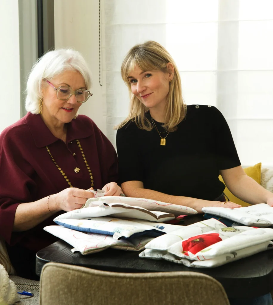 Maryse et Jeanne-Marie assise autour d'une table avec les capitons funéraires ANOBLIS en train de transmettre le savoir de l'entreprise de mère en fille